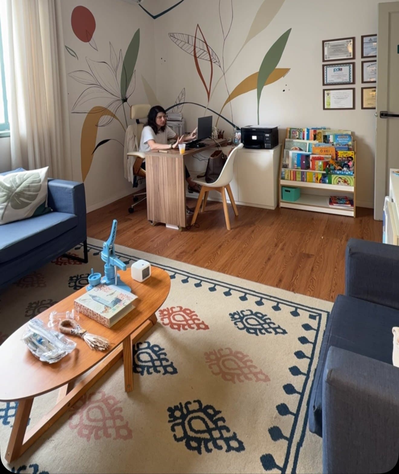 Sala de atendimento da égalité, com tapete, poltronas e estante de livros infantis